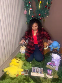 a woman kneeling on the floor with stuffed animals and a christmas tree