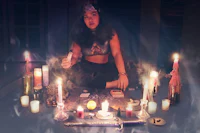 a woman sits on a table with candles in front of her